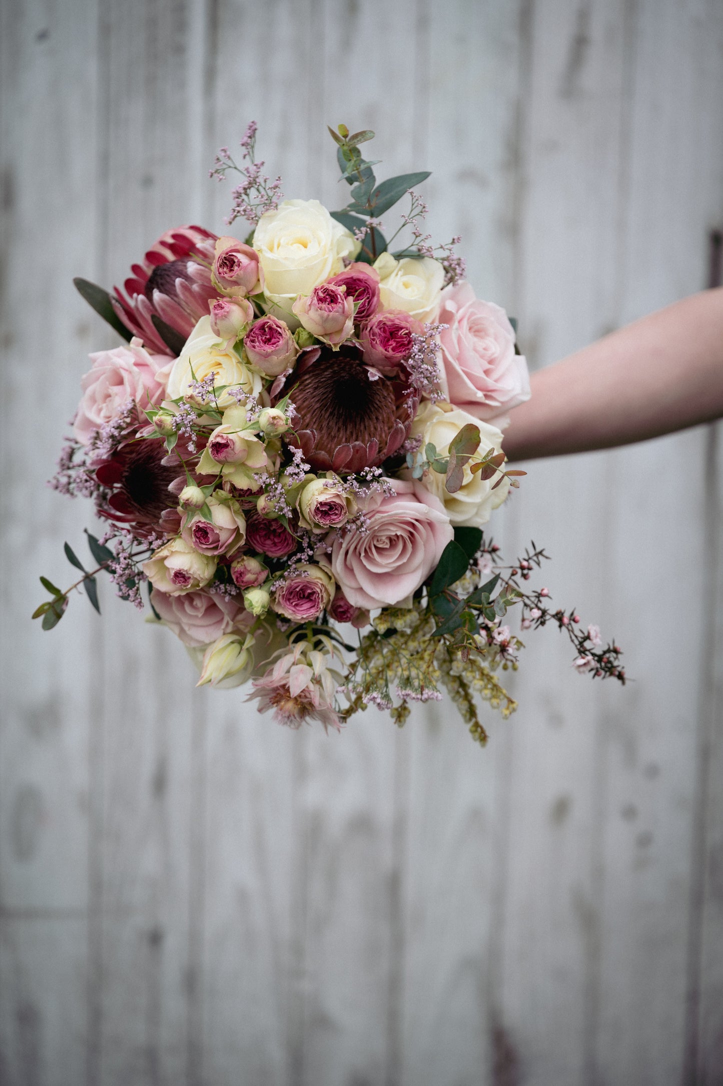 Bouquet of flowers held by a person against a wooden background